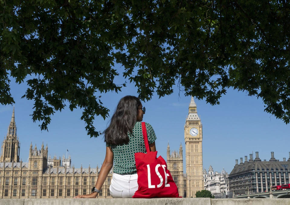 An LSE student sitting by the Thames in Westminster, London